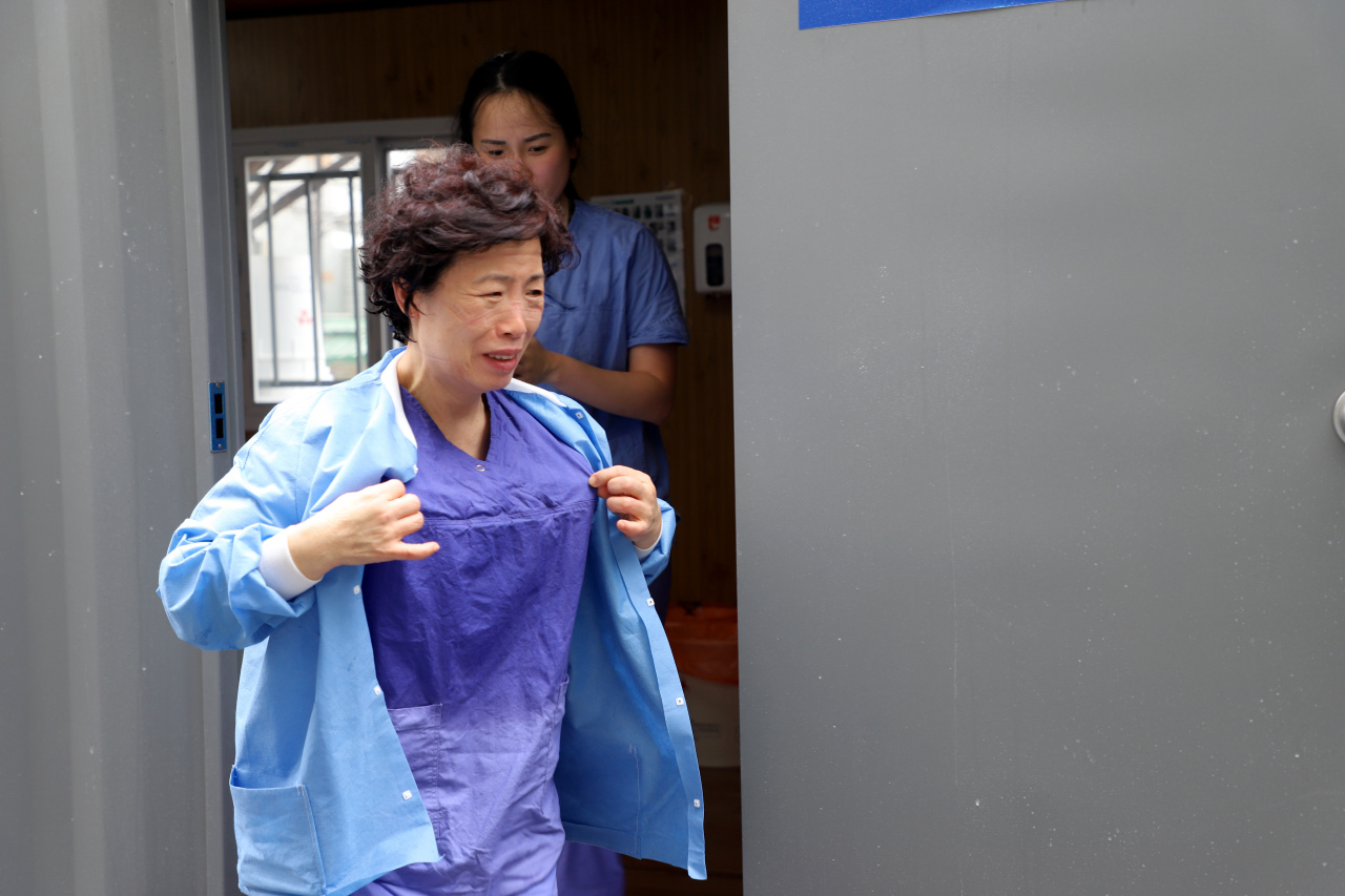 A medical staffer is seen drenched in sweat as she gets out of protective gear for a break in-between shifts. (Keimyung University Dongsan Hospital)