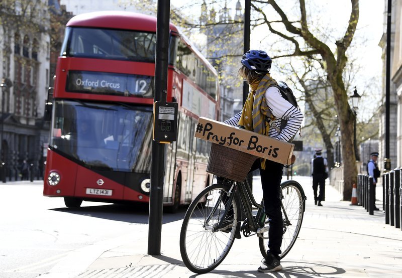 A woman shows a sign on her bicycle as British Prime Minister Boris Johnson is in intensive care fighting the coronavirus in London, Tuesday, April 7, 2020. Johnson was admitted to St Thomas' hospital in central London on Sunday after his coronavirus symptoms persisted for 10 days. Having been in hospital for tests and observation, his doctors advised that he be admitted to intensive care on Monday evening. The new coronavirus causes mild or moderate symptoms for most people, but for some, especially older adults and people with existing health problems, it can cause more severe illness or death. (AP-Yonhap)