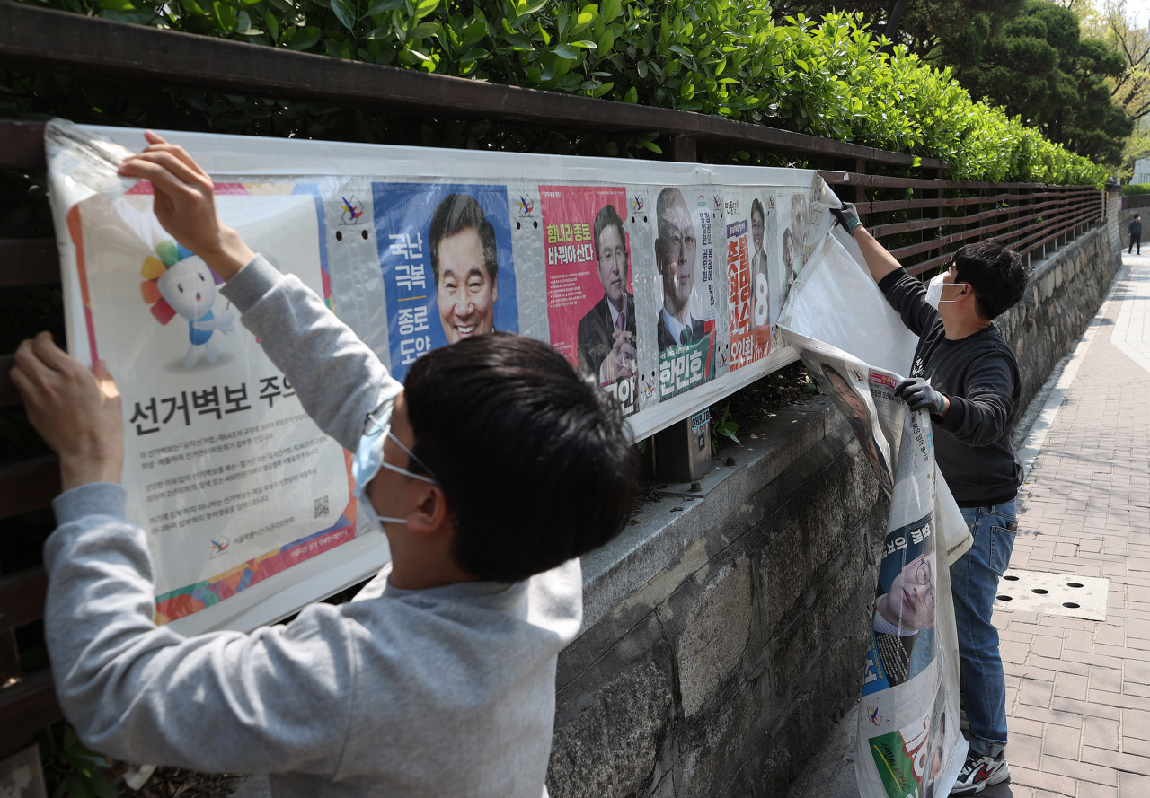 A civil worker removes campaign posters in central Seoul’s Jongno on Thursday, a day after nationwide parliamentary elections. (Yonhap)