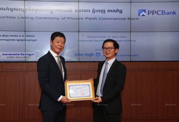 PPC Bank President Shin Chang-moo (left) and CSX CEO Hong Sok Hour pose for a photo with a copy of one of PPC Bank’s corporate bonds, at the CSX building in Phnom Penh on April 21. (JB Financial Group)