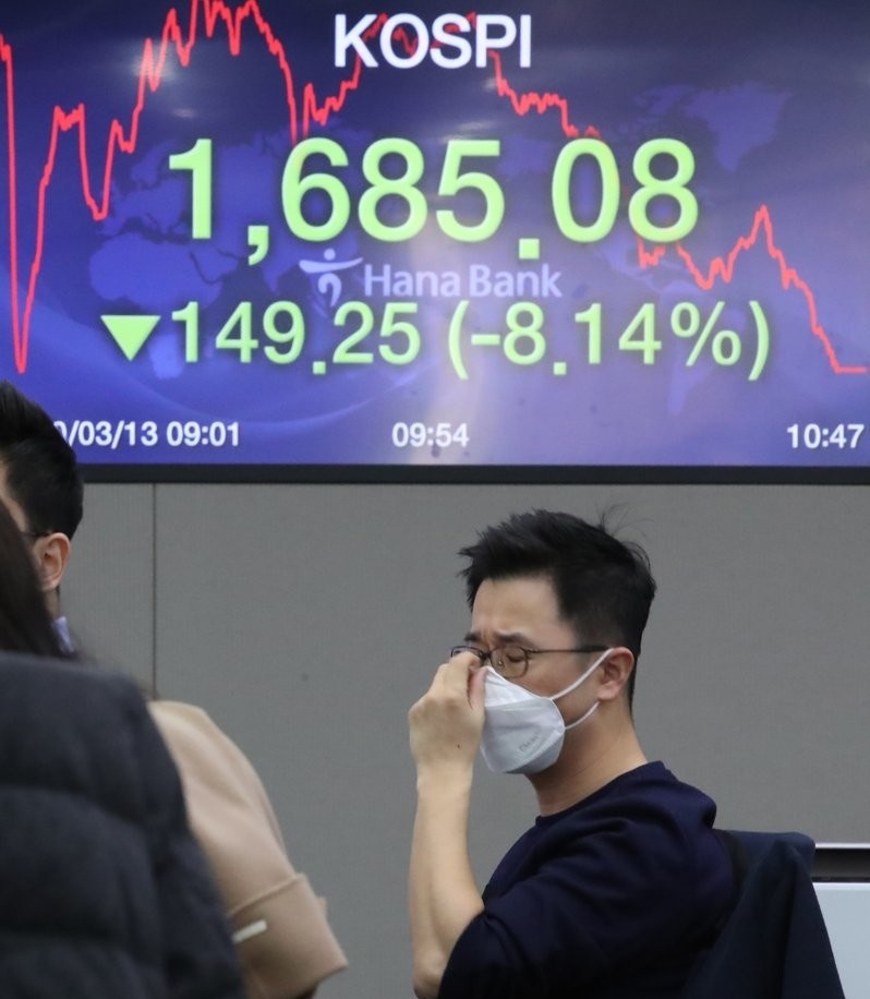 A currency dealer adjusts his mask at the dealing room of Hana Bank in Seoul on March 13, 2020. (Yonhap)