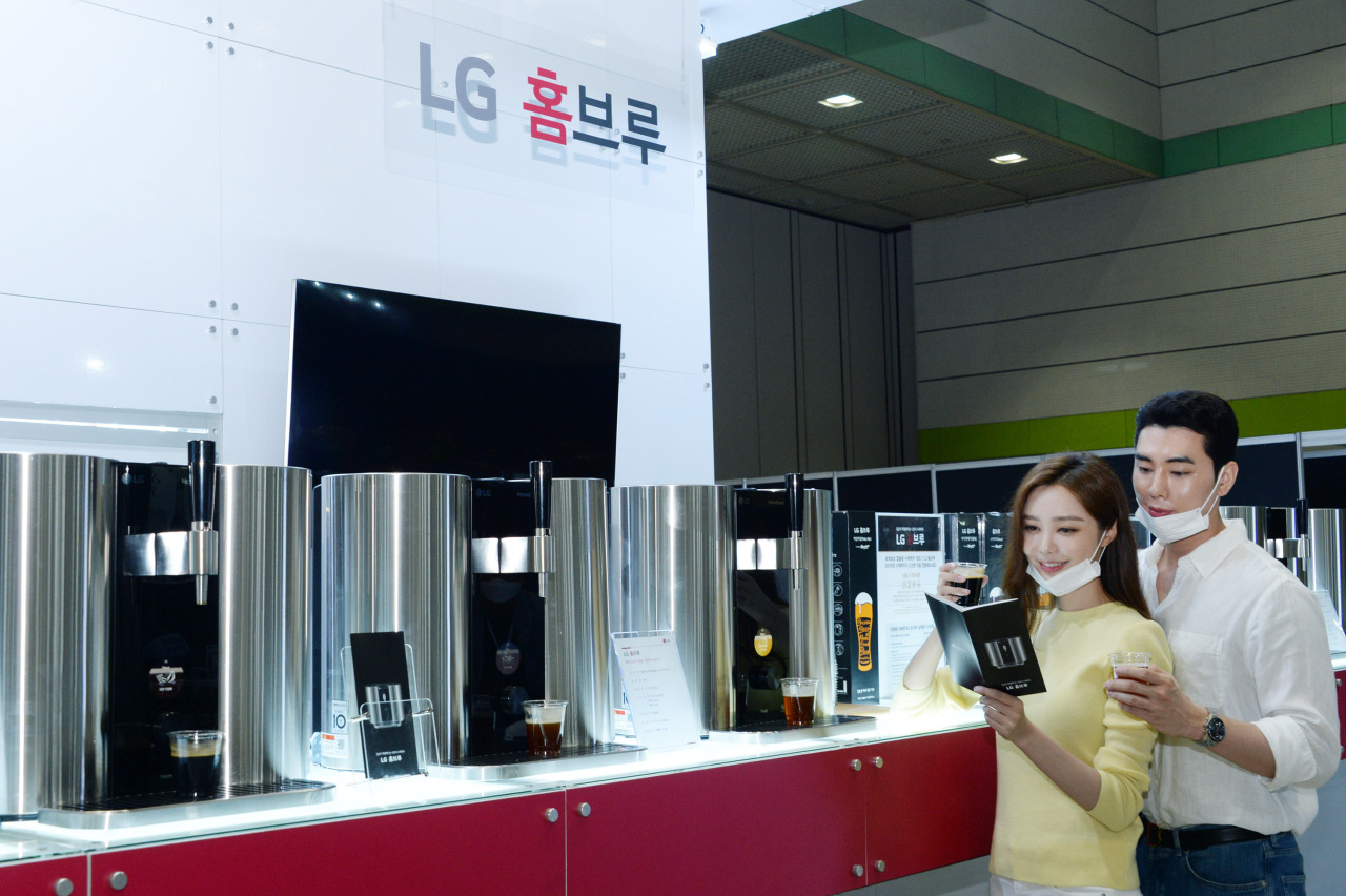 LG Electronics employees promote the LG HomeBrew machine at its booth at the Seoul International Wines & Spirits Expo 2020 at Coex in Seoul on Sunday. (LG Electronics)