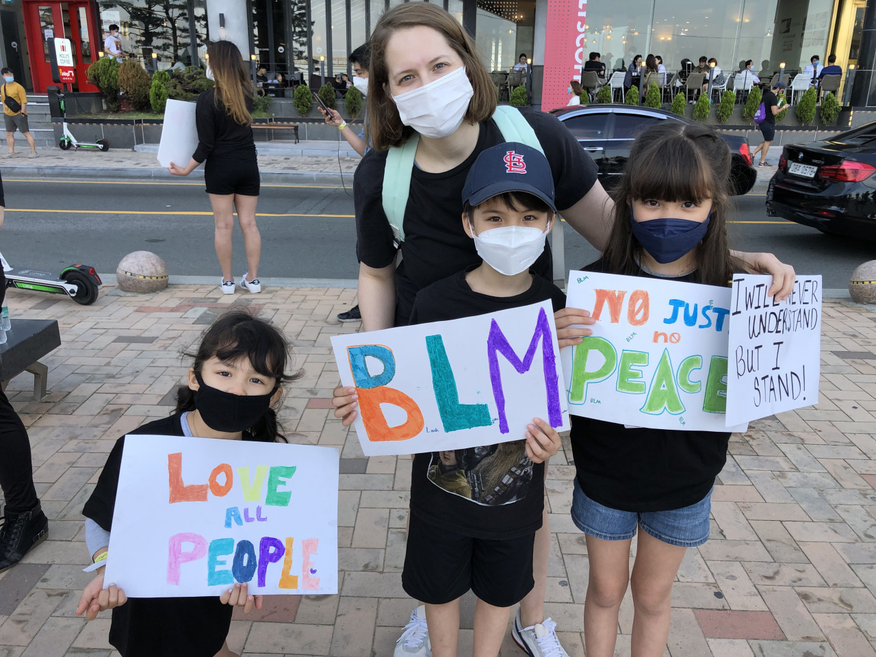 Mollie Triplett poses for a photo with her three children at the rally at Gwangalli Beach, Busan, Saturday.