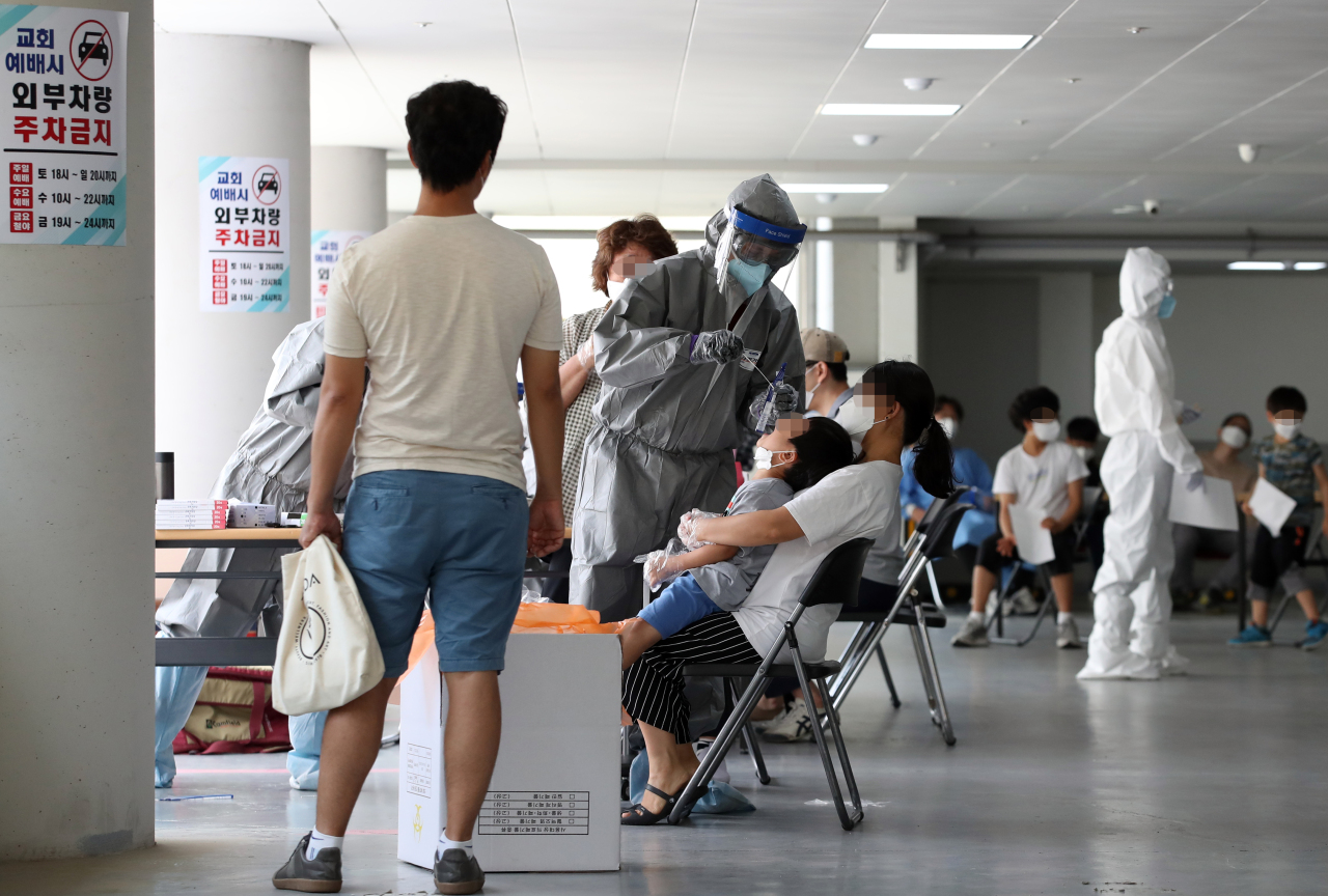 Seoul citizens go through new coronavirus tests at a temporary testing site established at Wangsung Church in the southeastern area of the capital on Friday. (Yonhap)