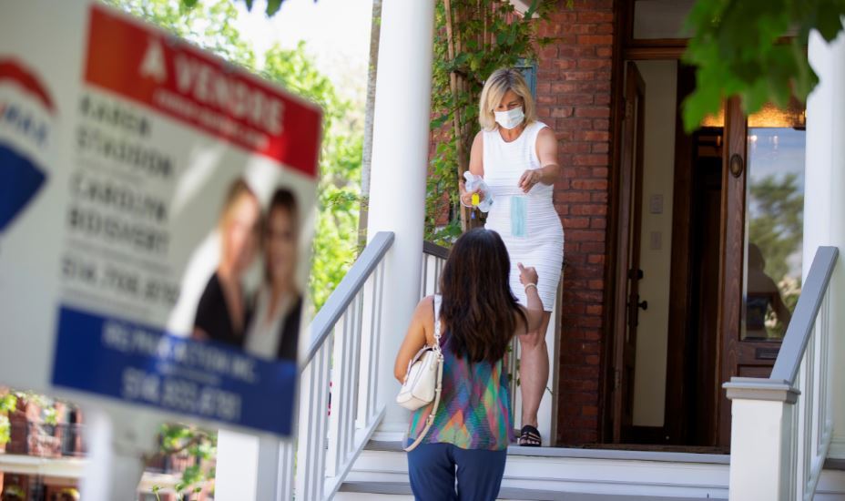 Real estate agent Karen Staddon hands out a mask to a client visiting a home for sale amid the coronavirus outbreak in Montreal, Canada on June 5. (Reuters)