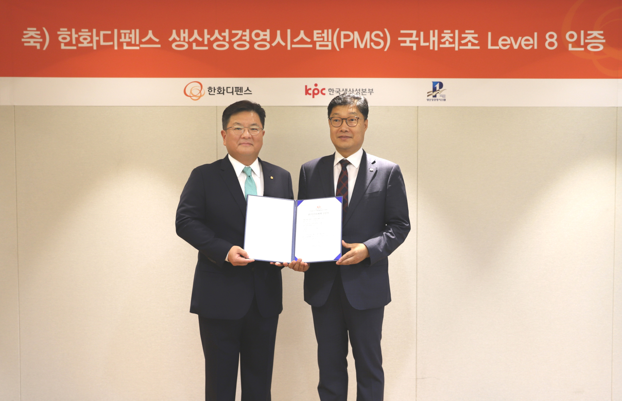 Hanwha Defense CEO Lee Sung-soo (left) accepts the company’s level 8 certification from Lee Jin-hwan, head of the Korea Productivity Center’s Productivity Innovation Institute. (Hanwha Defense)