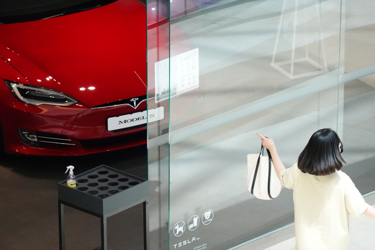 A woman walks past a Tesla dealership in Hanam, southeast of Seoul, on July 6. (Reuters-Yonhap)