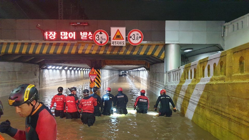 Firefighters launch rescue efforts Thursday at an underpass in Busan where three people died after being trapped inside due to heavy rainfall. (Busan Metropolitan Police Agency)