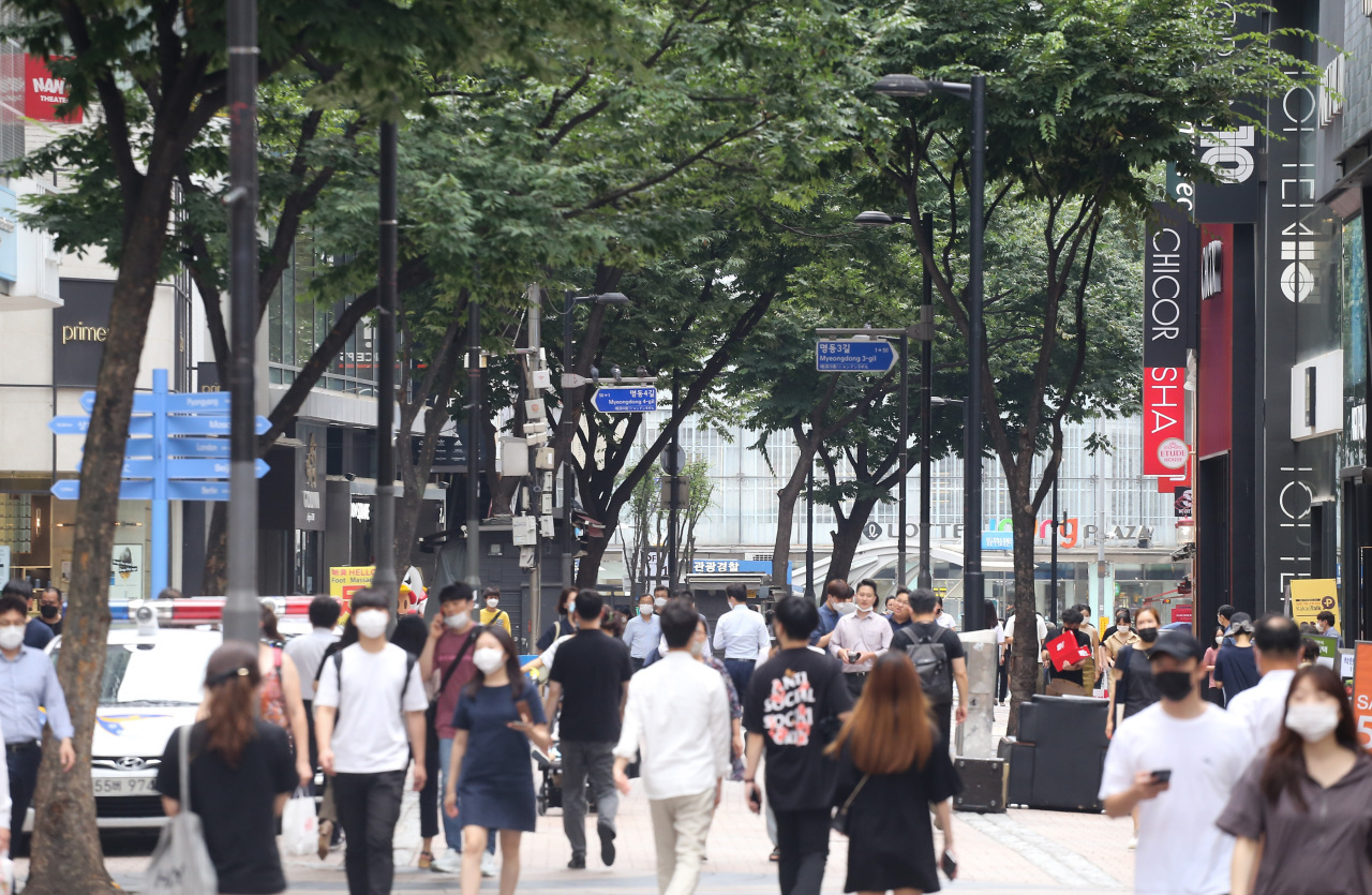People wearing masks walk across Myeong-dong street in Seoul. (Yonhap)