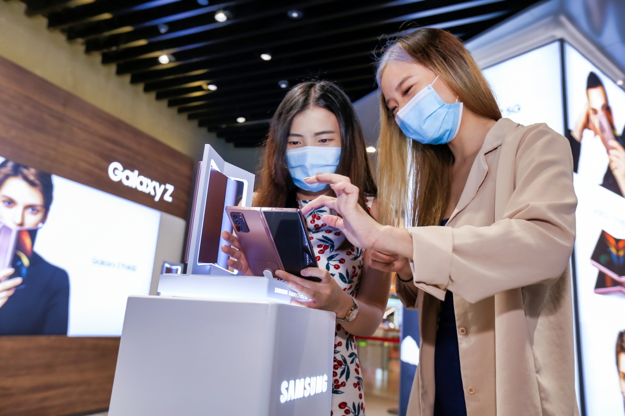 Consumers looking at the Galaxy Z Fold 2 foldable smartphone at Samsung Experience Store in ViVo City shopping mall in Singapore. (Yonhap)