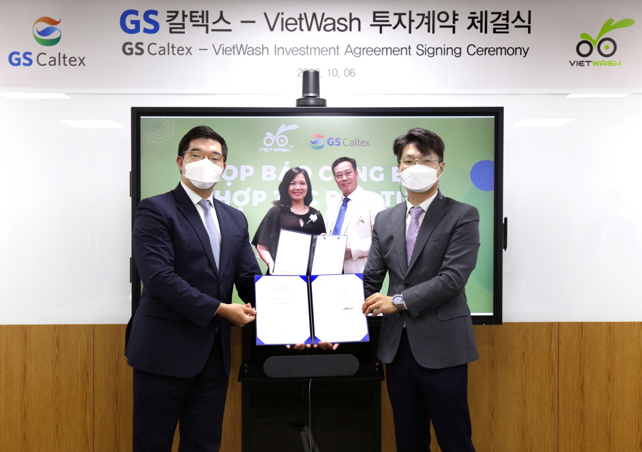 Huh Cheol-hong (left), vice president of GS Caltex Business Innovation and Cho Kwang-ok (right), vice president of GS Caltex Retail Business Planning, pose via video with Pham Thi Thanh Vy (left on video), CEO of VietWash, and Nguyen Van Canh (right on video), chairman of Petrolimex Saigon after signing an investment agreement on Tuesday. (GS Caltex)