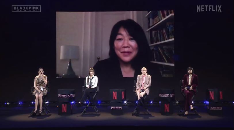 Members of Blackpink hold a global conference about documentary “Blackpink: Light Up the Sky,” joined through videoconference by director Caroline Suh, on Tuesday in Seoul. (Screen capture of livestreamed video on YouTube)
