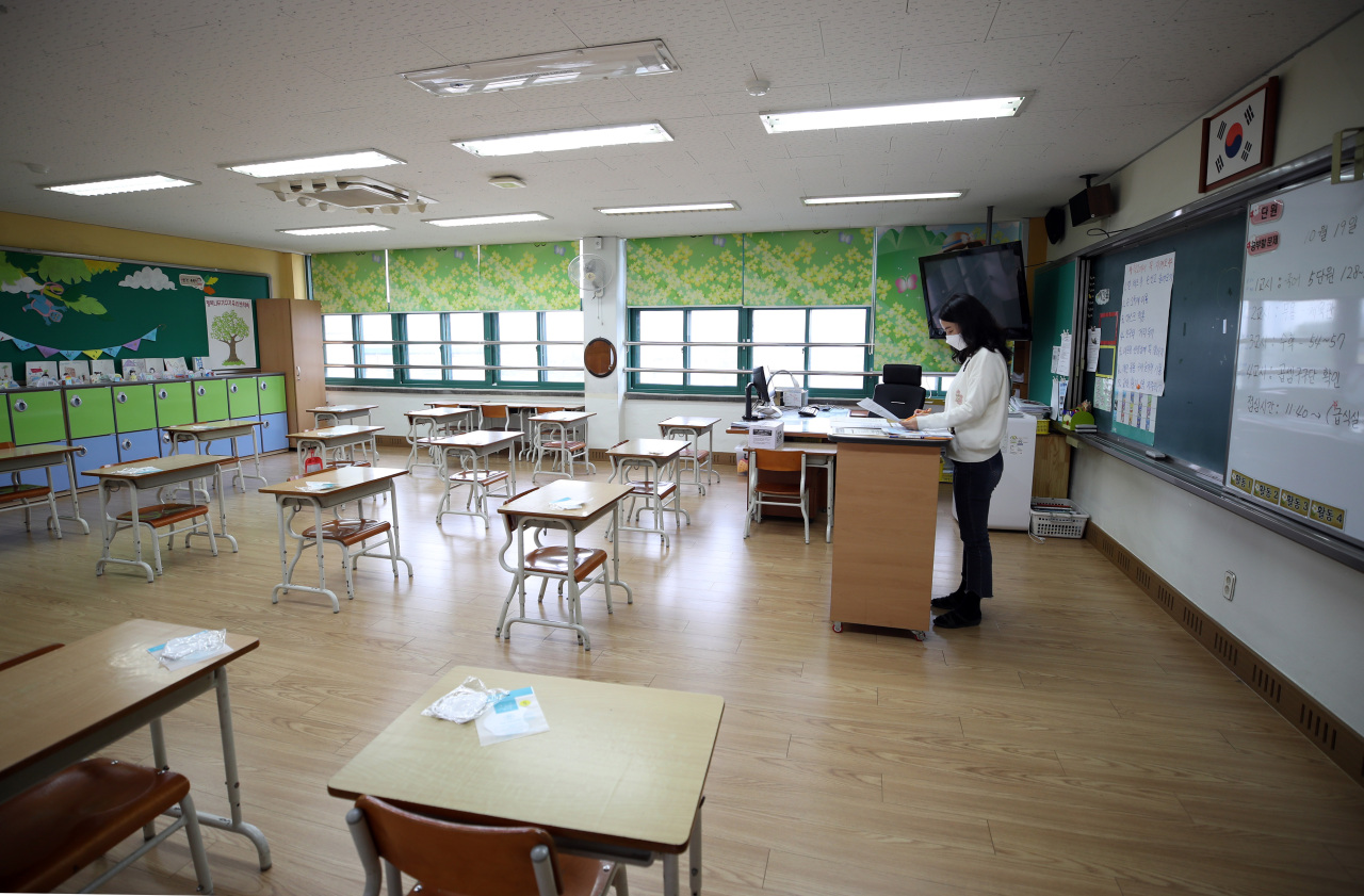A Seoul elementary school teacher prepares for in-person classes on Friday, as more students are expected to return to classrooms starting next week. (Yonhap)