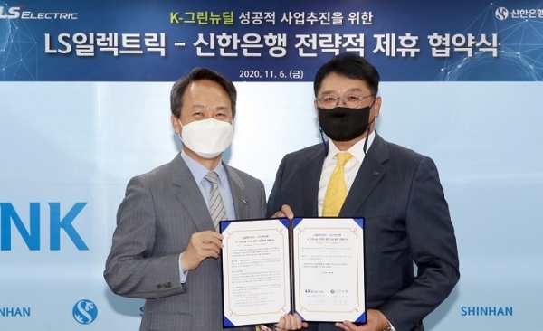 Jin Ok-dong (left), CEO of Shinhan Bank, and Koo Ja-kyun, chairman of LS Electric, pose after signing an agreement to collaborate on green energy projects, Friday in Seoul. (Shinhan Bank)