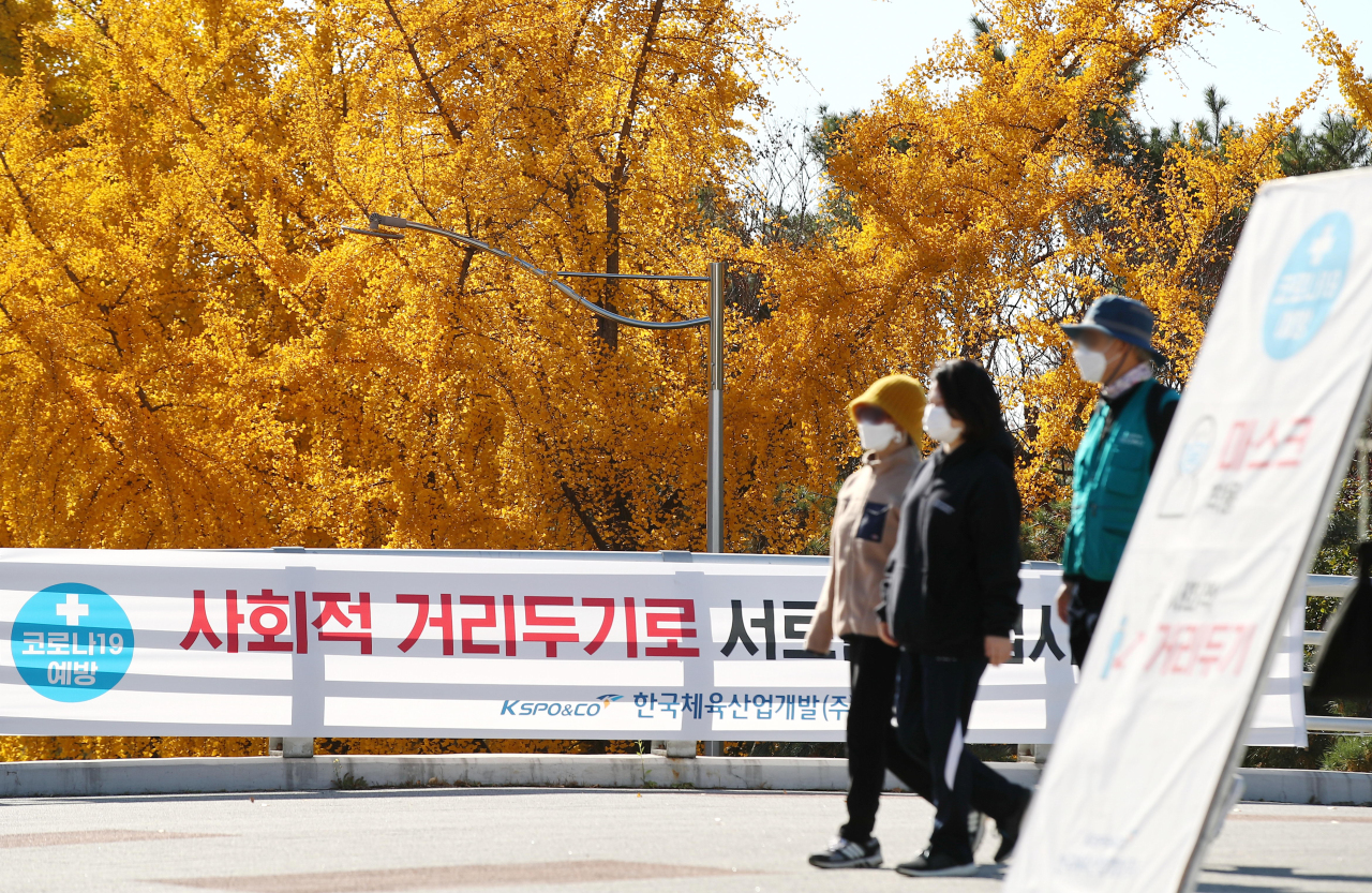 Citizens wearing protective masks walk around a park in eastern Seoul on Sunday. (Yonhap)