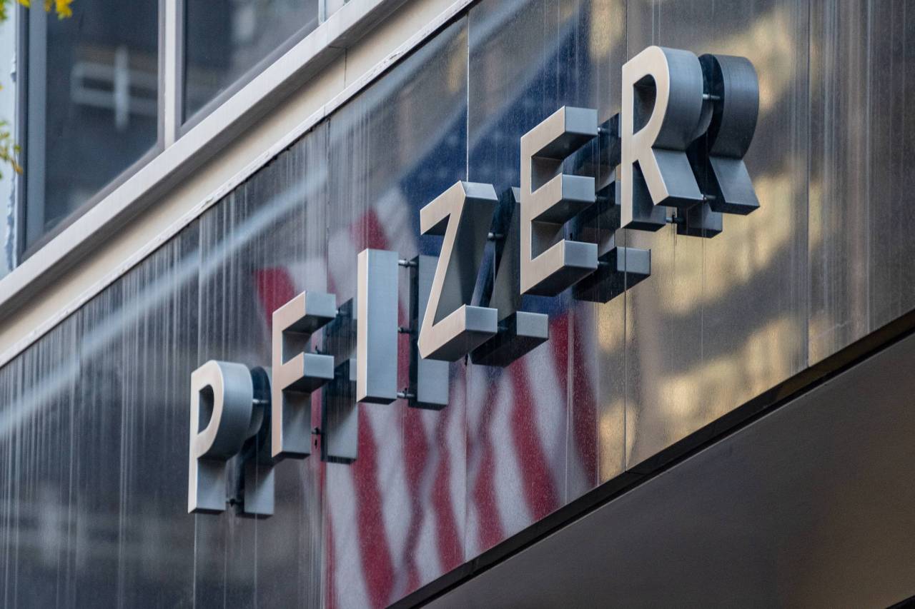People walk by the Pfizer headquarters on Monday in New York City. Pharmaceutical company Pfizer announced positive early results on its COVID-19 vaccine trial and has proven to be 90 percent effective in preventing infection of the virus. (AFP-Yonhap)