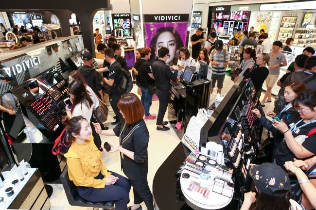 Customers try makeup products displayed at the Korean cosmetics zone of the Shinsegae Duty Free store in Myeong-dong, Seoul. (Shinsegae Duty Free)