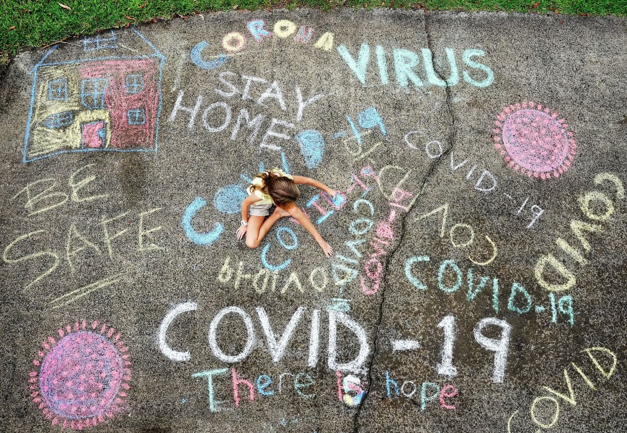 A girl drawing and writing letters with chalk at a house in the Gold Coast. (Dave Hunt of the Australian Associated Press)