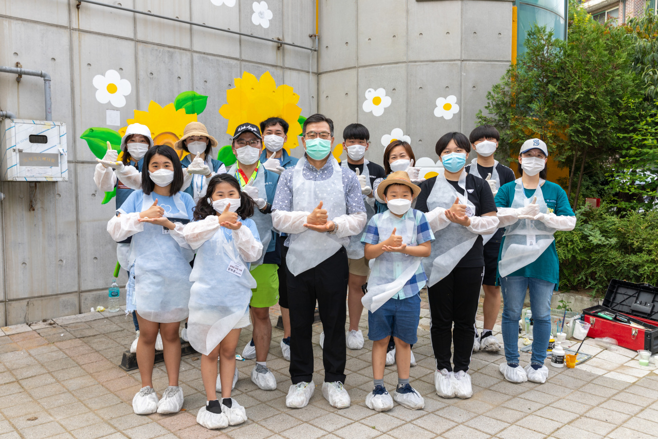 Korea Investment & Securities CEO Jung Il-mun (fourth from left) poses for photo after volunteering for wall painting projects with the company’s members and their families in June. (KIS)