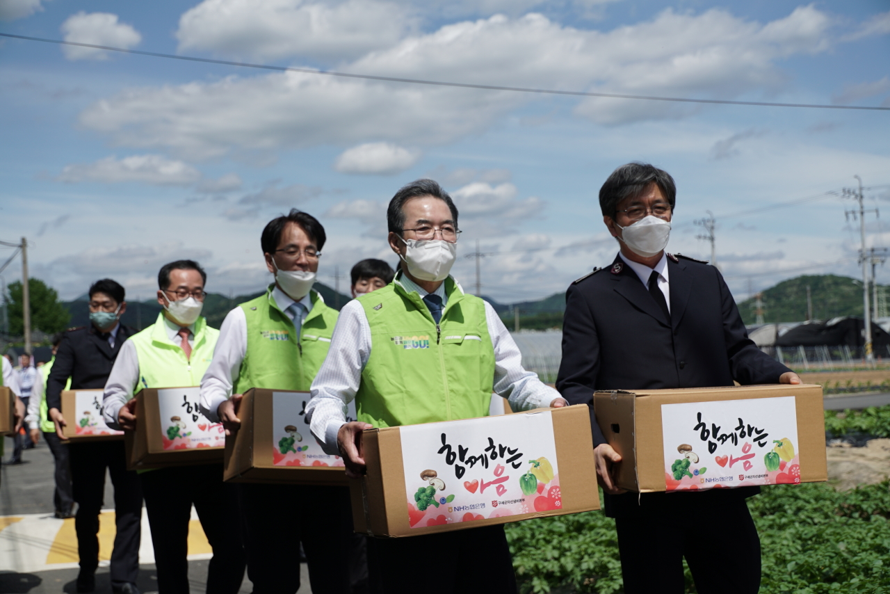Lee Sung-hee (left, first row), chairman of National Agricultural Cooperative Federation, the parent company of NongHyup Financial Group, Chang Man-hee (right, first row), commissioner of the Korean Salvation Army and NongHyup Bank CEO Son Byung-hwan (left, second row) deliver agricultural products to low-income households in farm villages in Goyang, Gyeonggi Province, May. (NongHyup Bank)