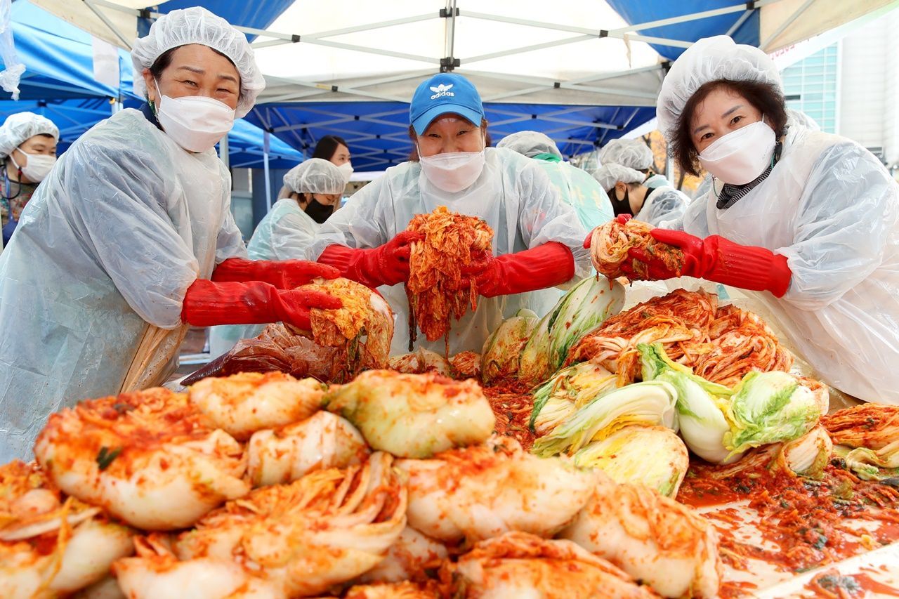 A group of volunteers poses with kimchi, a traditional Korean side dish normally made of fermented cabbage, salt and hot peppers, during an event held in eastern Seoul on Nov. 18. (Seongdong Ward)
