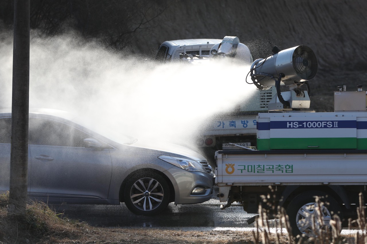 Agricultural officials disinfect an automobile near a farm located in Sangju, 270 km southeast of Seoul, on Wednesday. (Yonhap)