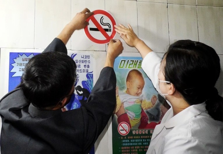 North Korean officials place a nonsmoking sticker on a wall on May 31. (North's Korean Central TV)