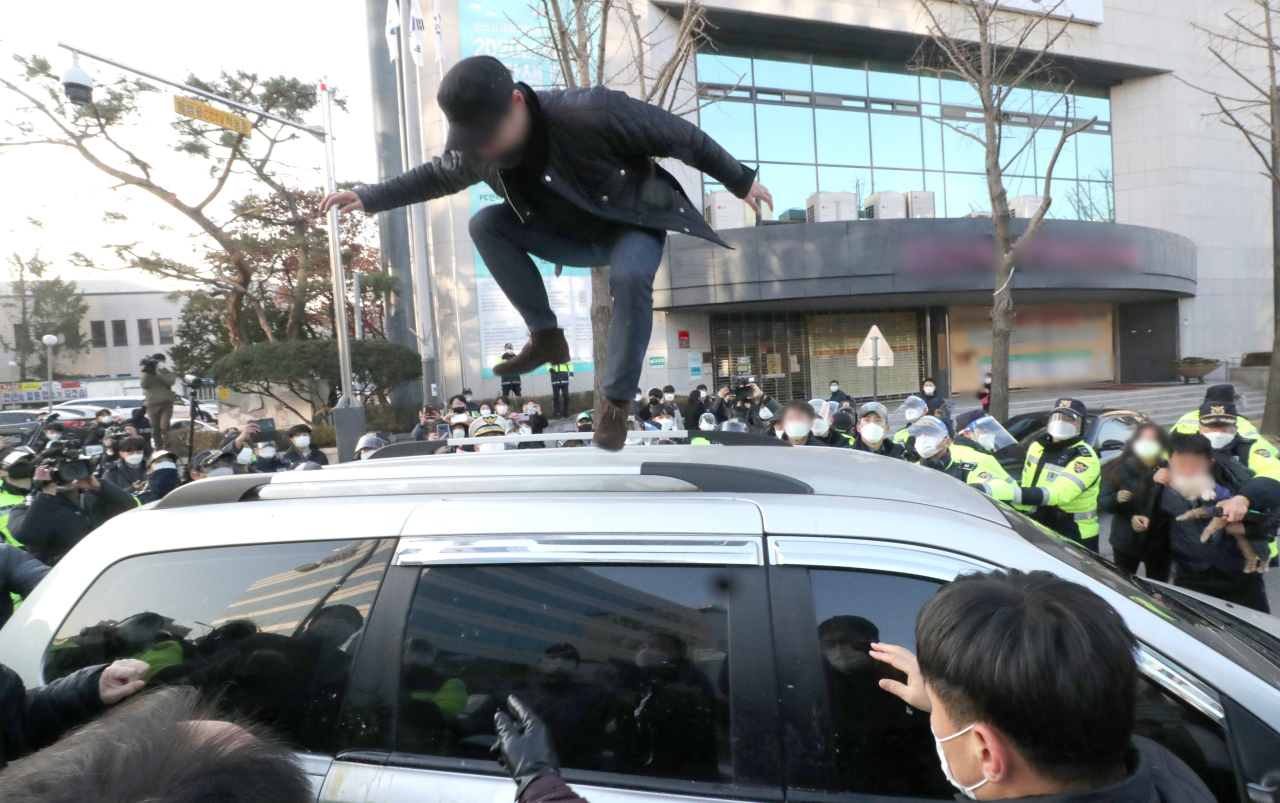 A YouTuber stomps on top of the vehicle escorting child rapist Cho Doo-soon on Dec. 12. (Yonhap)