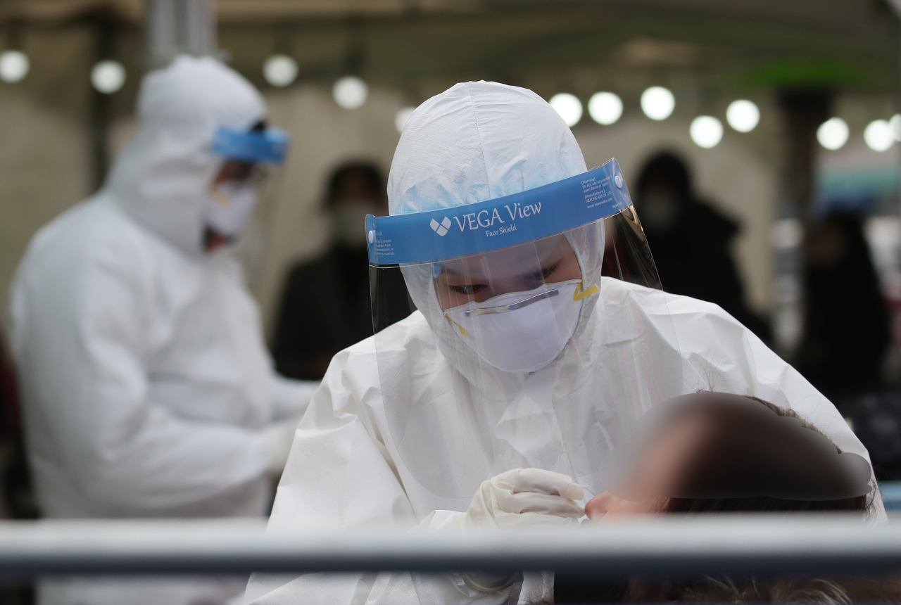 A medical worker conducts a COVID-19 test at a makeshift virus testing clinic on Tuesday. (Yonhap)