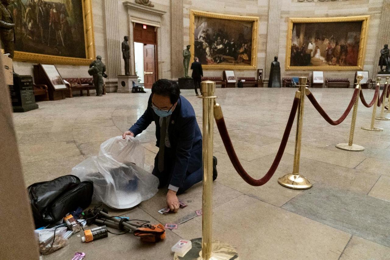 This AP photo shows Rep. Andy Kim (D-NJ) cleaning up debris and personal belongings strewn across the floor of the rotunda in the early morning hours of Thursday, a day after protesters stormed the U.S. Capitol in Washington. (AP-Yonhap)