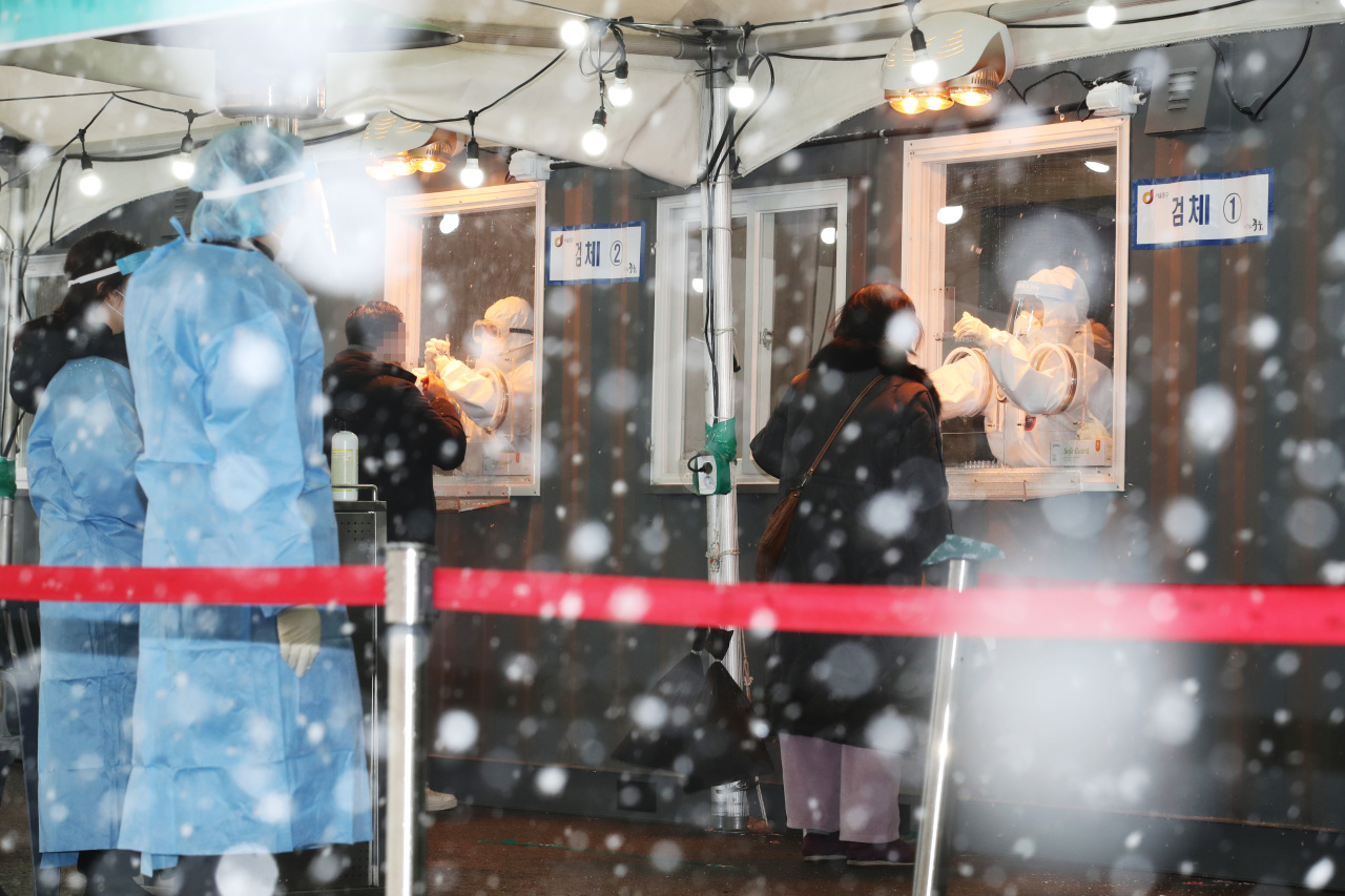 Citizens undergo coronavirus tests at a makeshift clinic in front of Seoul Station in central Seoul amid heavy snow on Tuesday. (Yonhap)