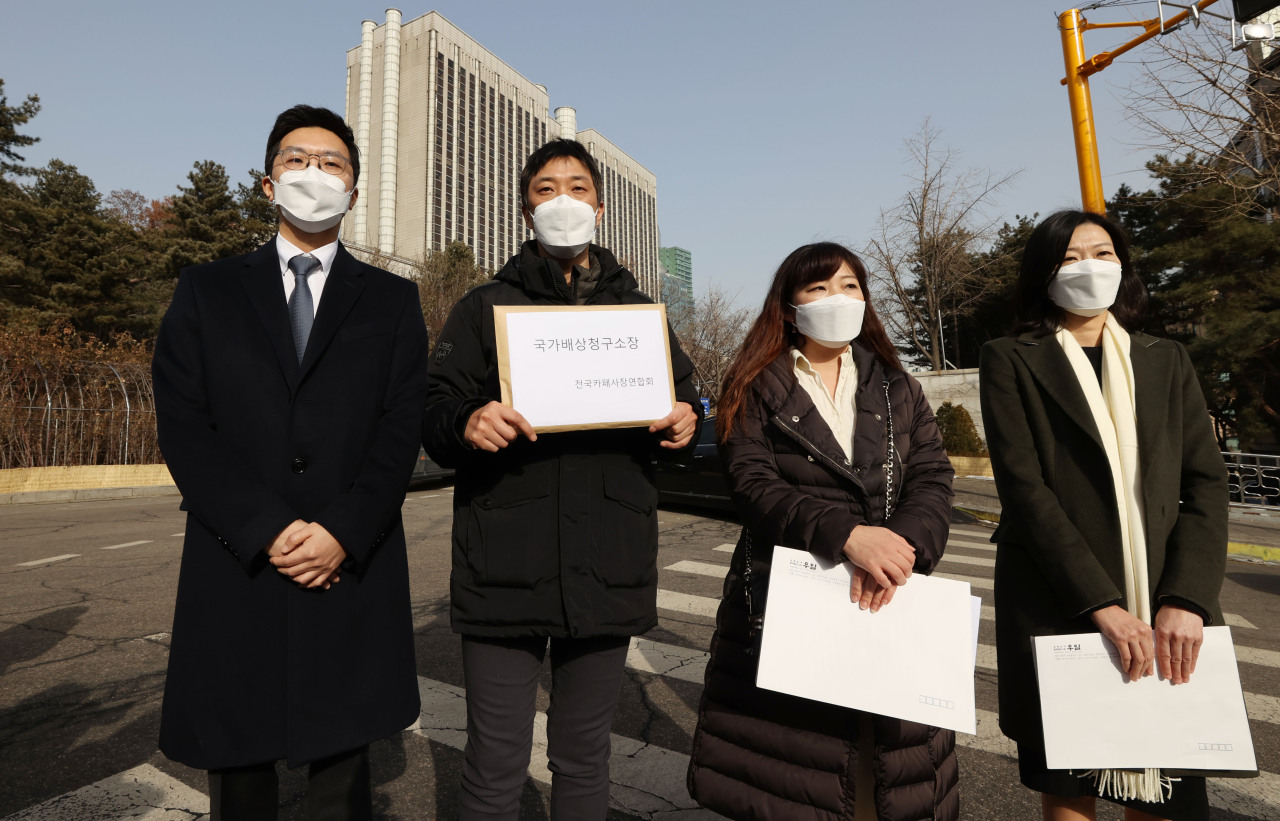 Member of a cafe owners' association hold a press conference outside the Seoul Central District Court on Thursday, before filing a damage suit against the government at the court. (Yonhap)