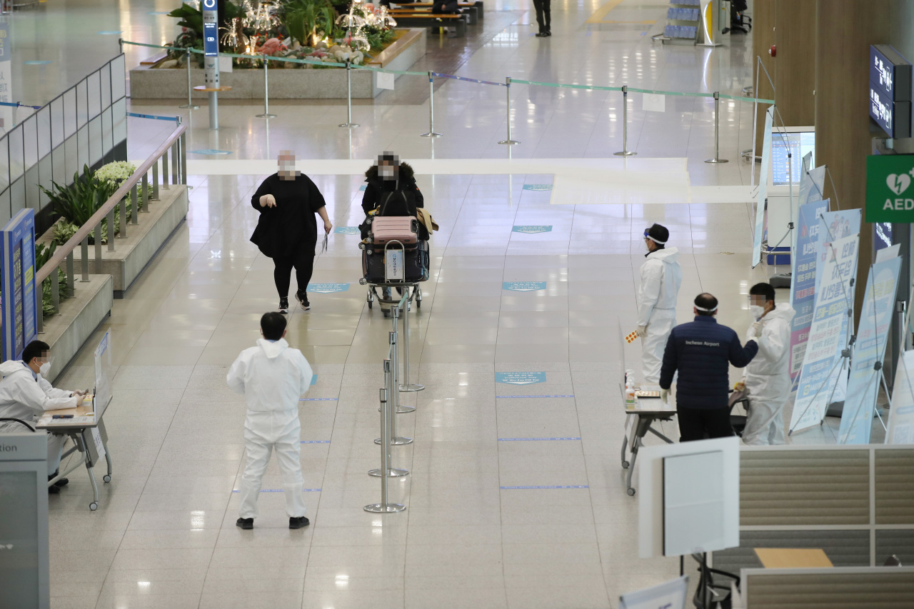Medical workers meet passengers arriving at Incheon Airport on Jan. 10. (Yonhap)