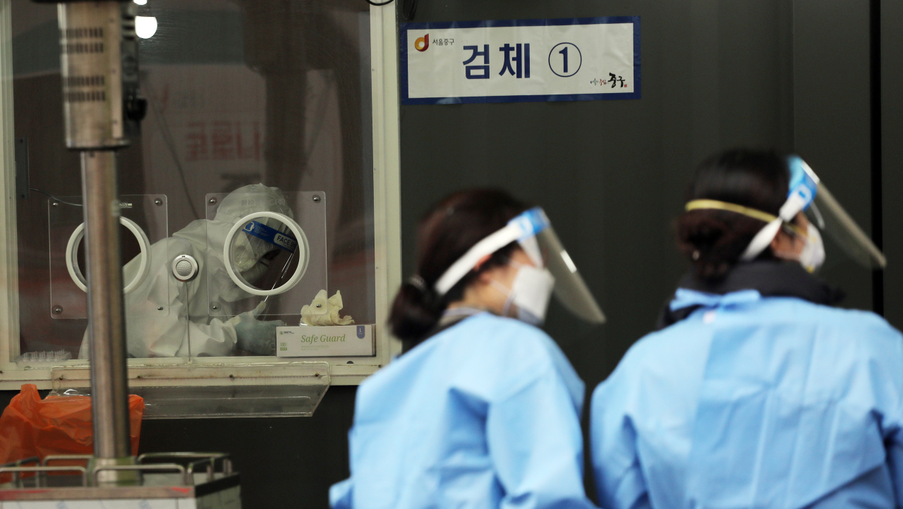 Medical workers prepare to administer coronavirus tests at a makeshift testing facility in Seoul on Sunday. (Yonhap)