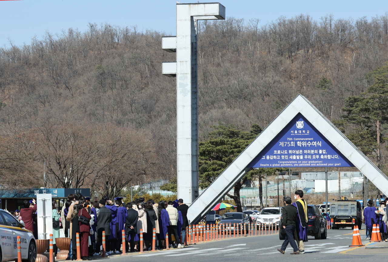Students and family members take photos at the main enterance to Seoul National University after a graduation ceremony last Friday. (Yonhap)