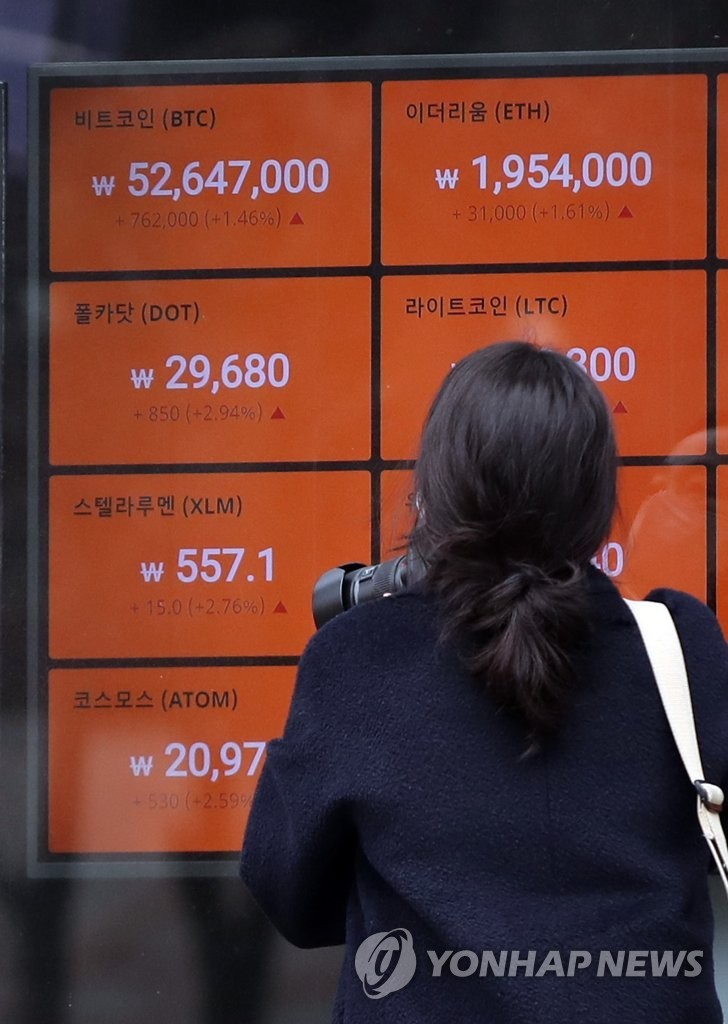 A woman looks at the electronic board of a cryptocurrency exchange in Seoul, showing the price of Bitcoin soaring, during a trading session Feb. 15. (Yonhap)