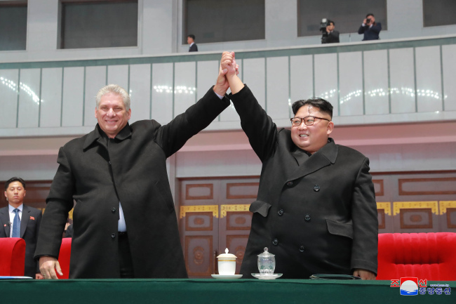 North Korean leader Kim Jong-un (R) and his visiting Cuban counterpart Miguel Mario Diaz-Canel Bermudez hold up their hands as they watch a mass games performance in Pyongyang on Nov. 5, 2018, in this photo captured from the North's Rodong Sinmun newspaper. (Rodong Sinmun)