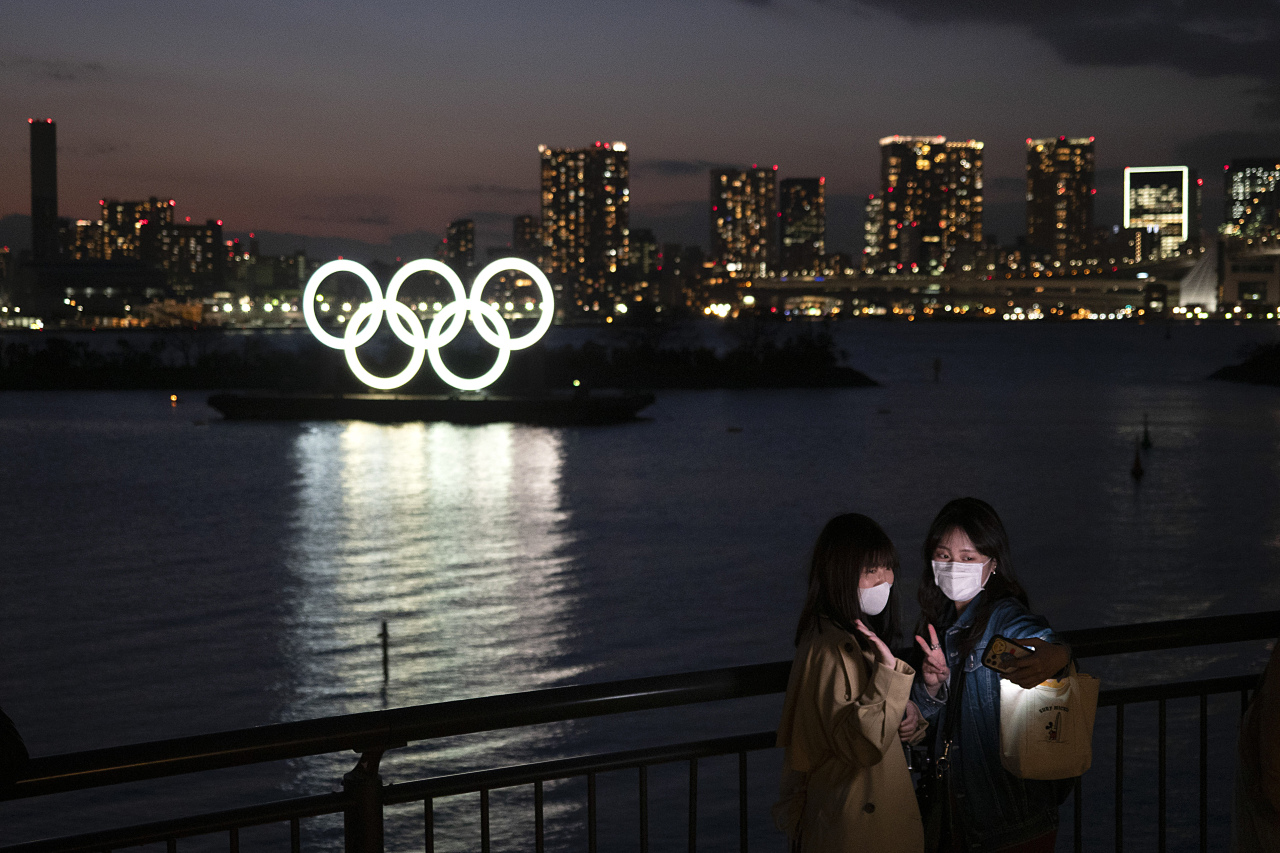 Two women take a selfie with the Olympic rings in the background in the Odaiba section of Tokyo, Thursday, March 12, 2020. (AP-Yonhap)