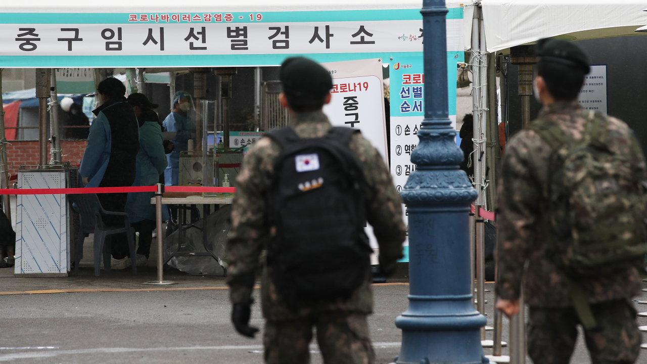 In this file photo, taken Feb. 16, 2021, service members head to an outdoor coronavirus test center at Seoul Station. (Yonhap)