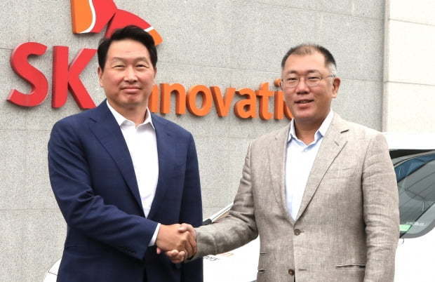 Hyundai Motor Group Executive Vice Chairman Chung Euisun (right) shakes hands with SK Group Chairman Chey Tae-won at SK Innovation’s electric vehicle battery plant in Seosan, South Chungcheong Province, in July. (Hyundai Motor)