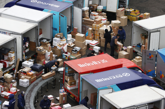 Workers sort goods at a parcel distribution center in Seoul. (Yonhap)