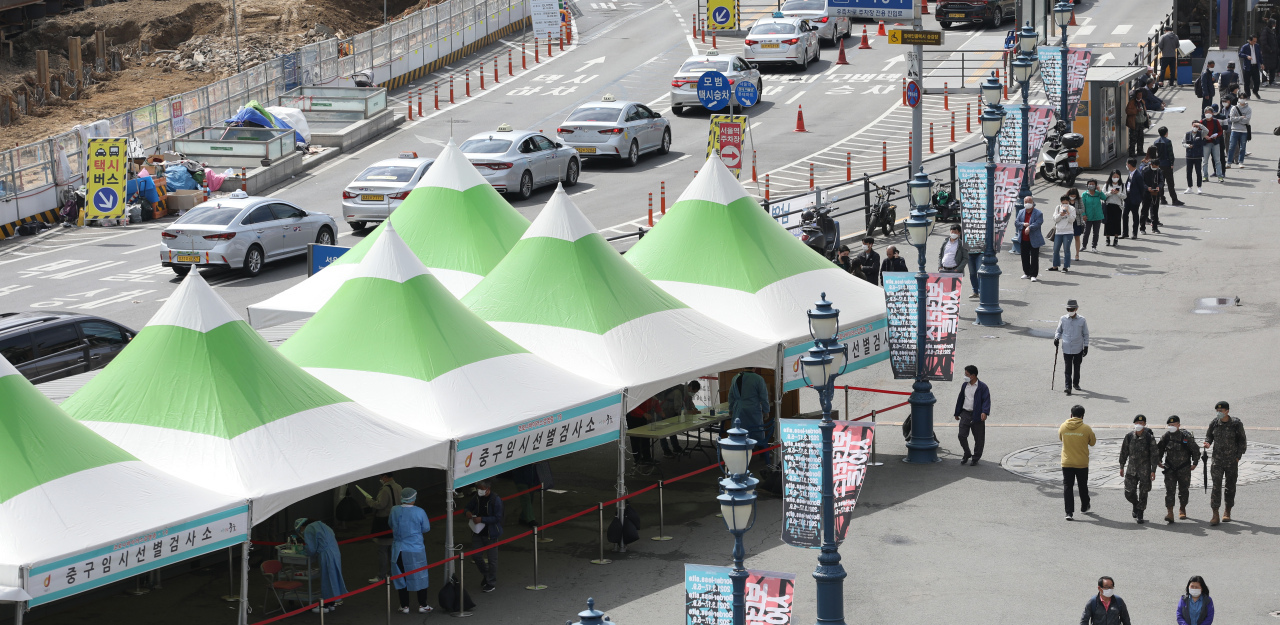 This photo, taken on Friday, shows citizens waiting in line to receive COVID-19 tests at a makeshift testing site set up in front of Seoul Station. (Yonhap)