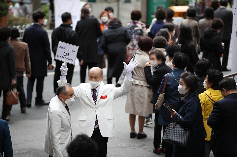 Worshipers wait in lines at a church in western Seoul to participate in Easter Mass amid the pandemic on Sunday. (Yonhap)