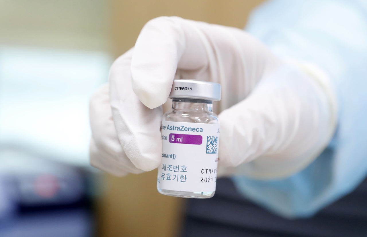 Health care worker at a Seoul inoculation center holds out a vial of AstraZeneca vaccine. (Yonhap)