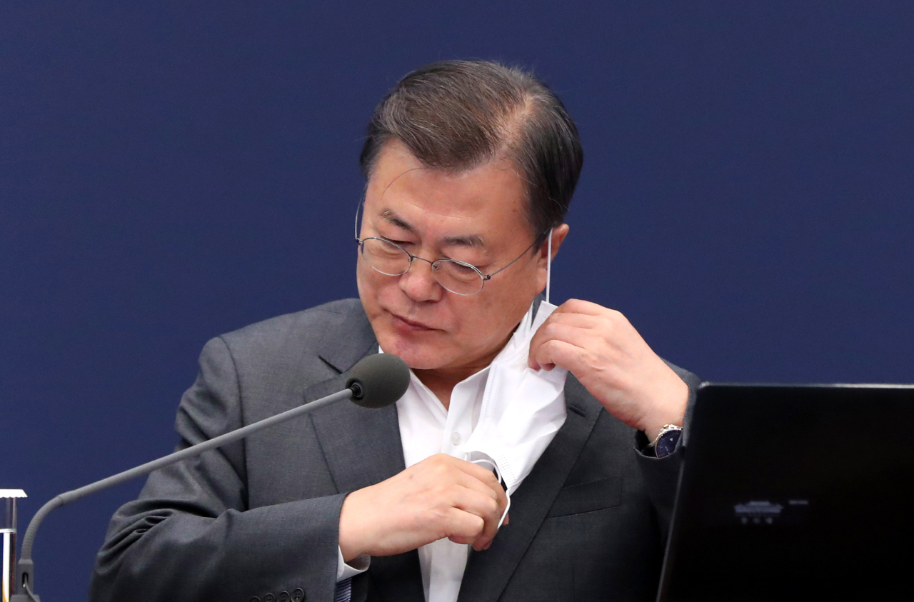 President Moon Jae-in takes off a mask before making opening remarks during a meeting with senior secretaries at Cheong Wa Dae in Seoul on Monday. (Yonhap)