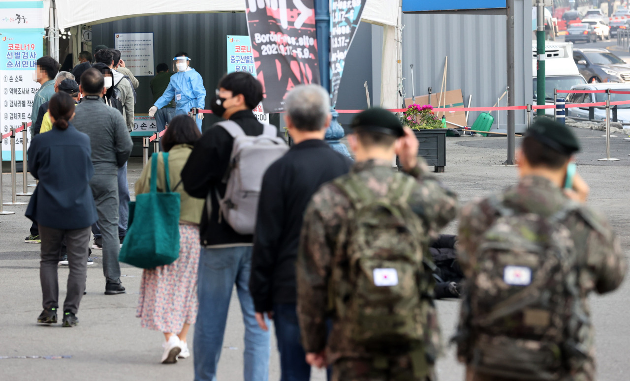 People stand in line to receive coronavirus tests at a makeshift clinic in front of Seoul Station on April 7, 2021. (Yonhap)
