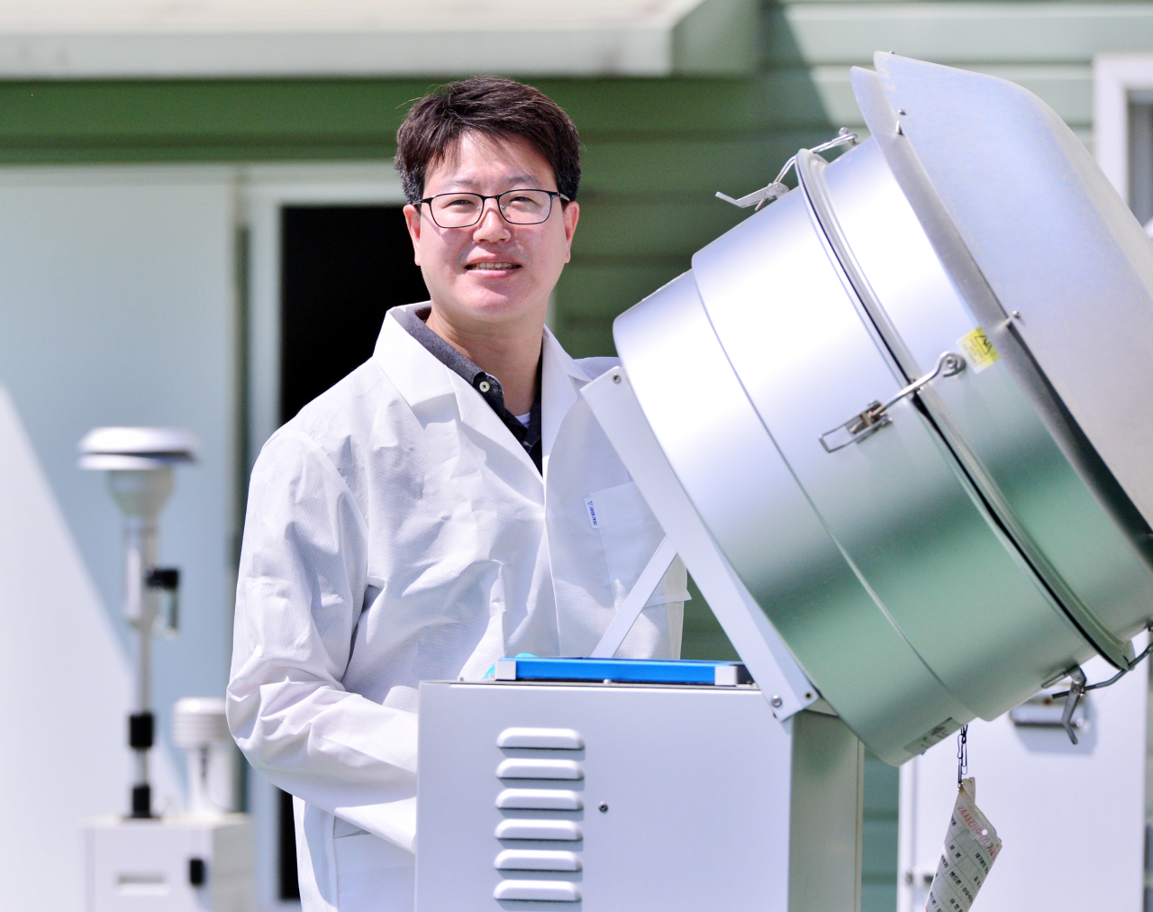 Kim Ji-seok, senior researcher at the Korea Atomic Energy Research Institute, poses next to a fine dust monitoring station in Daejeon. (Park Hyun-koo/The Korea Herald)