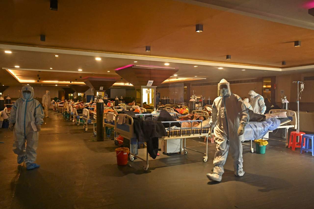 Health workers wearing personal protective equipment (PPE kit) attends to COVID-19 coronavirus positive patients inside a banquet hall temporarily converted into a covid care centre in New Delhi on Thursday. (AFP-Yonhap)