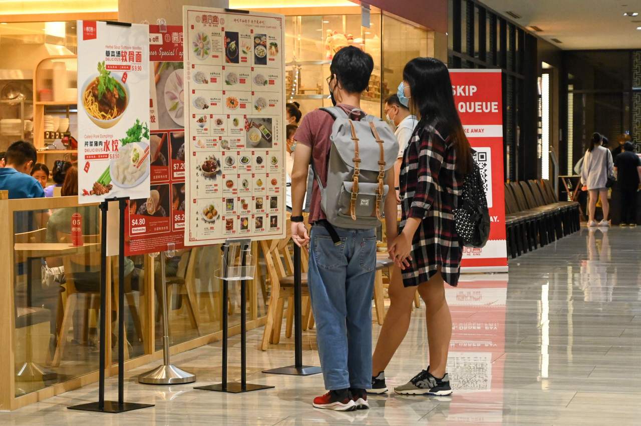 People look at the menu displayed outside a restaurant in a shopping mall in Singapore on Saturday, ahead of tightening restrictions over concerns in a rise in Covid-19 coronavirus cases.(AFP)