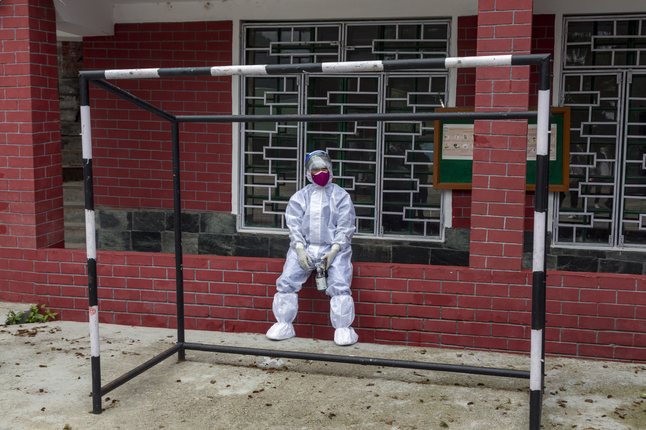 A medical staff from the Tibetan Delek Hospital wearing a protective suit rests during a camp organised to test exile Tibetans for COVID-19 in the compound of a school in Dharmsala, India, Wednesday. (AP-Yonhap)